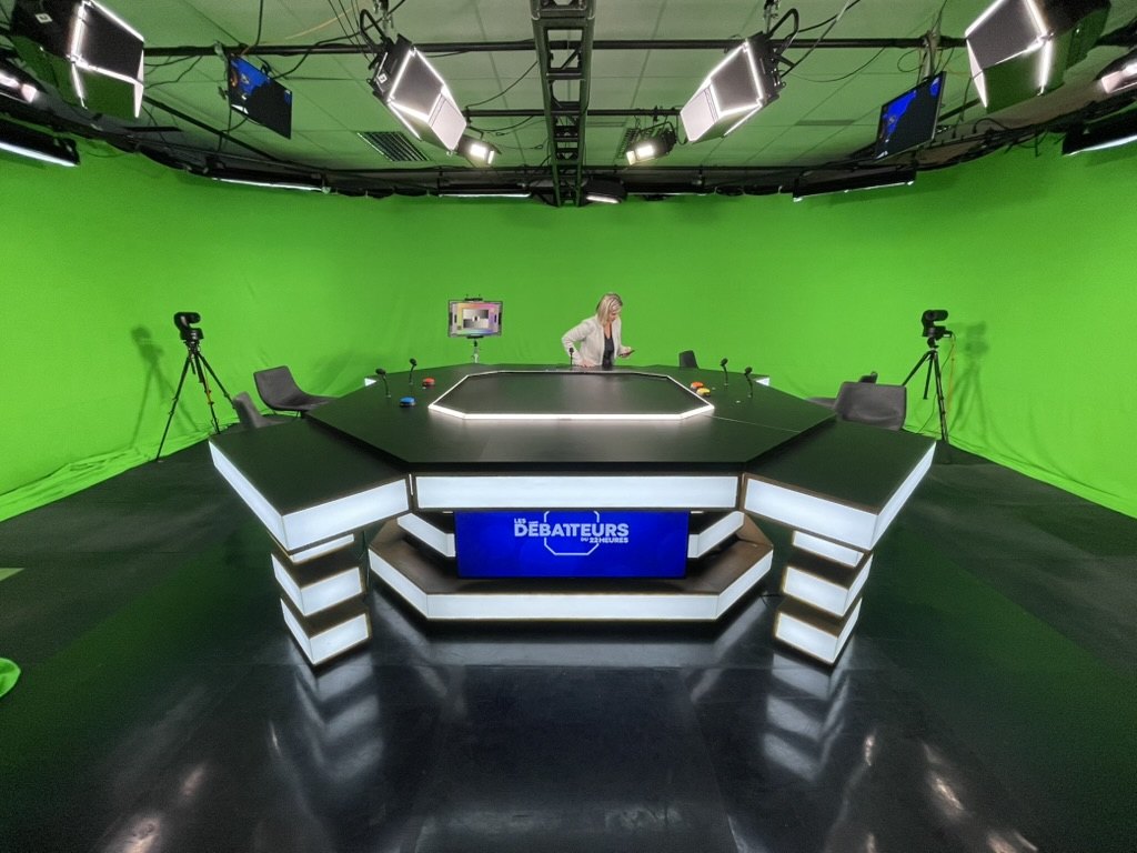The Débatteurs virtual set: illuminated desk at the centre of a green cyc, cameras and lighting rigged